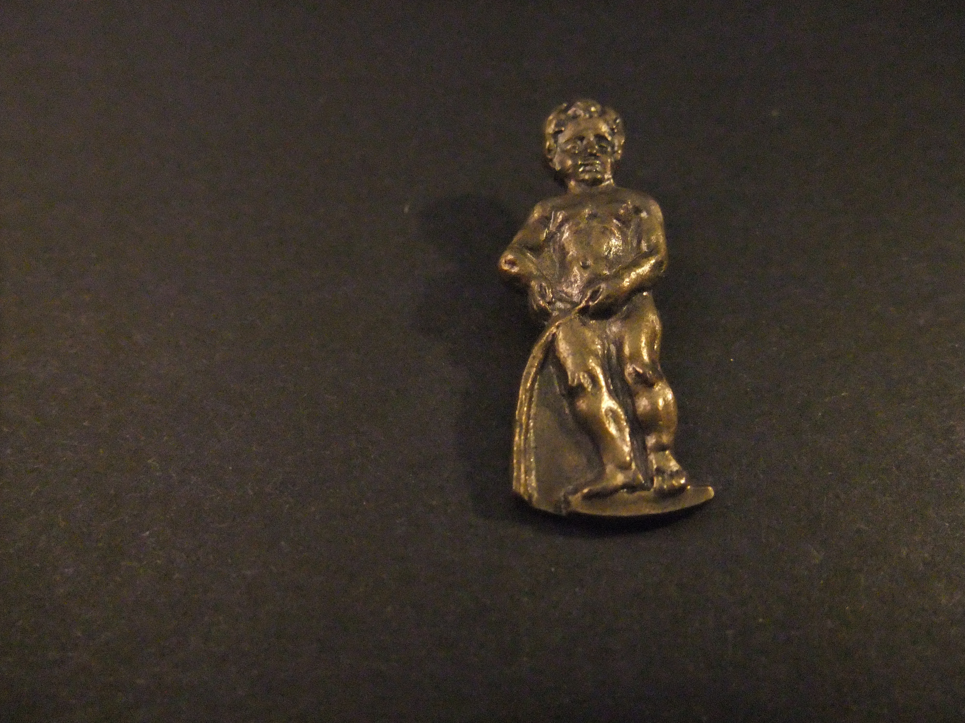 Manneken Pis  standbeeldje van een plassend jongetje in het centrum van Brussel ( koperkleurig